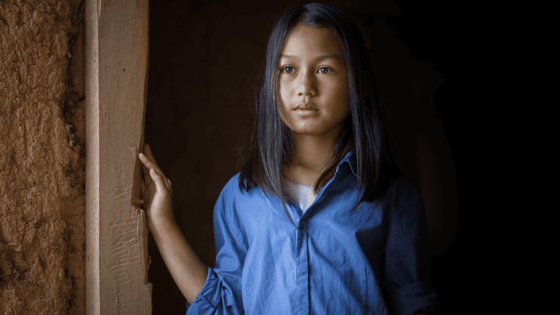 A girl stands in a doorframe in Cambodia