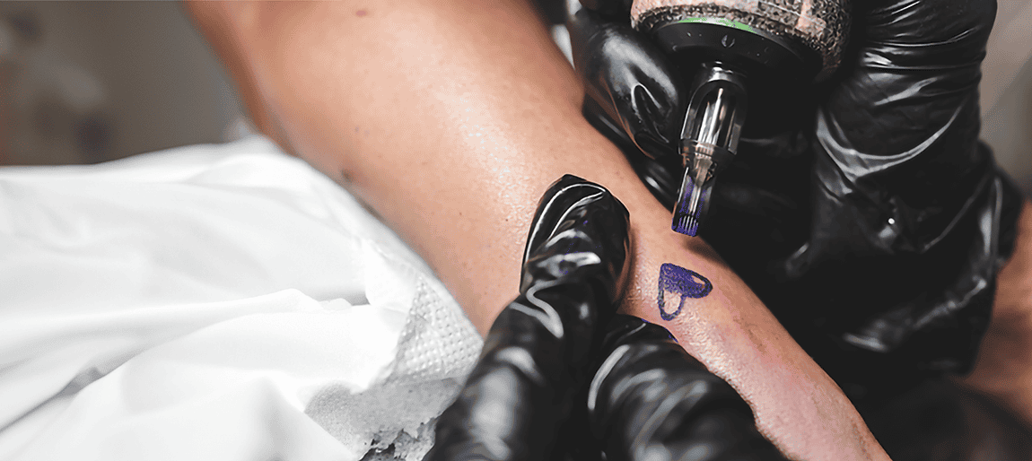 A woman's arm is being tattooed with a heart