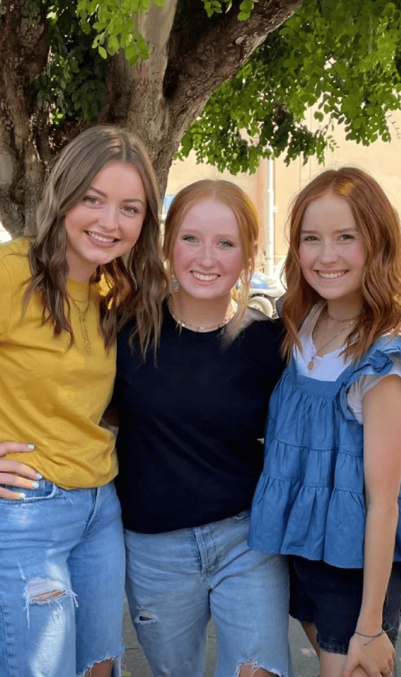 3 girls pose behind a table of Our Rescue info at a highschool